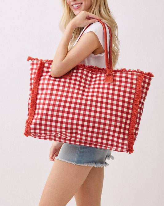 Woman holding a red and white checkered bag against a light background.