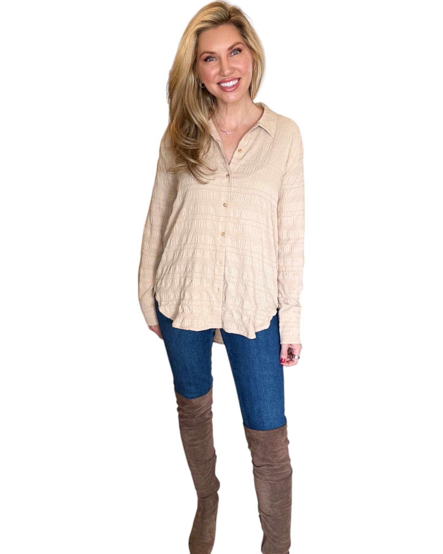 Blonde woman smiling while wearing the Almond Button Down Shirt paired with blue jeans. The shirt features a textured fabric, long sleeves, and a relaxed fit with a curved hem.
