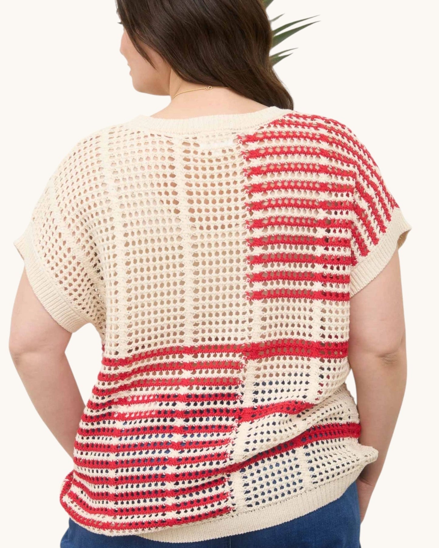 Woman wearing a red and white striped open knit crochet top on a white background, back view.