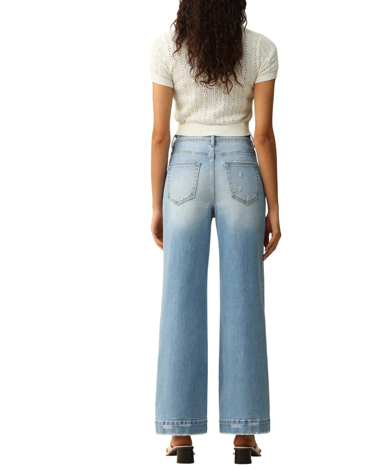 Person wearing light blue jeans and a white top on a white background.