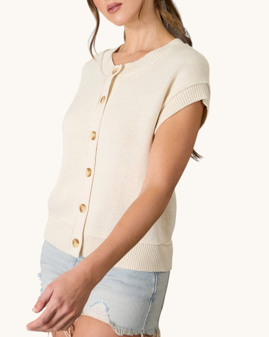Woman wearing a cream-colored cardigan with button details on a white background.