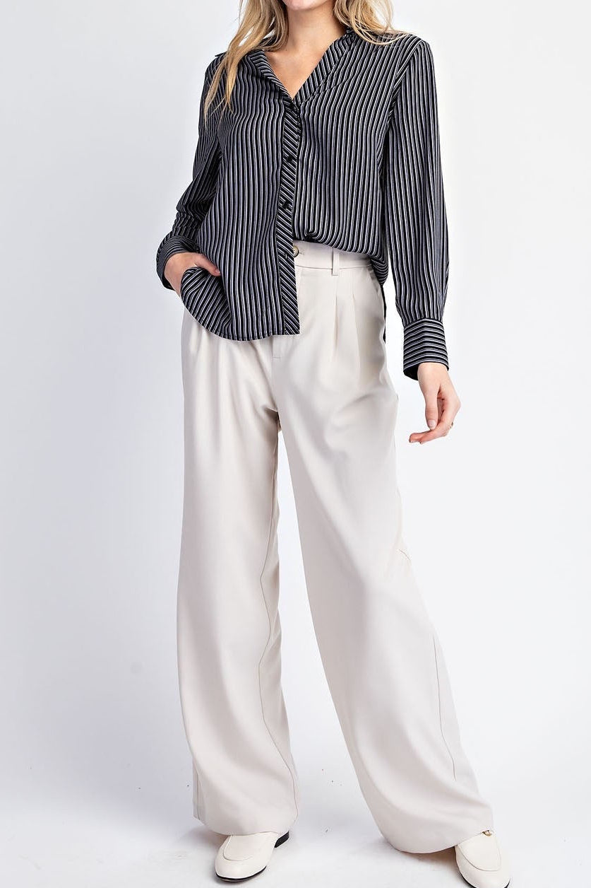 Woman wearing a black and white striped shirt with white pants on a white background.