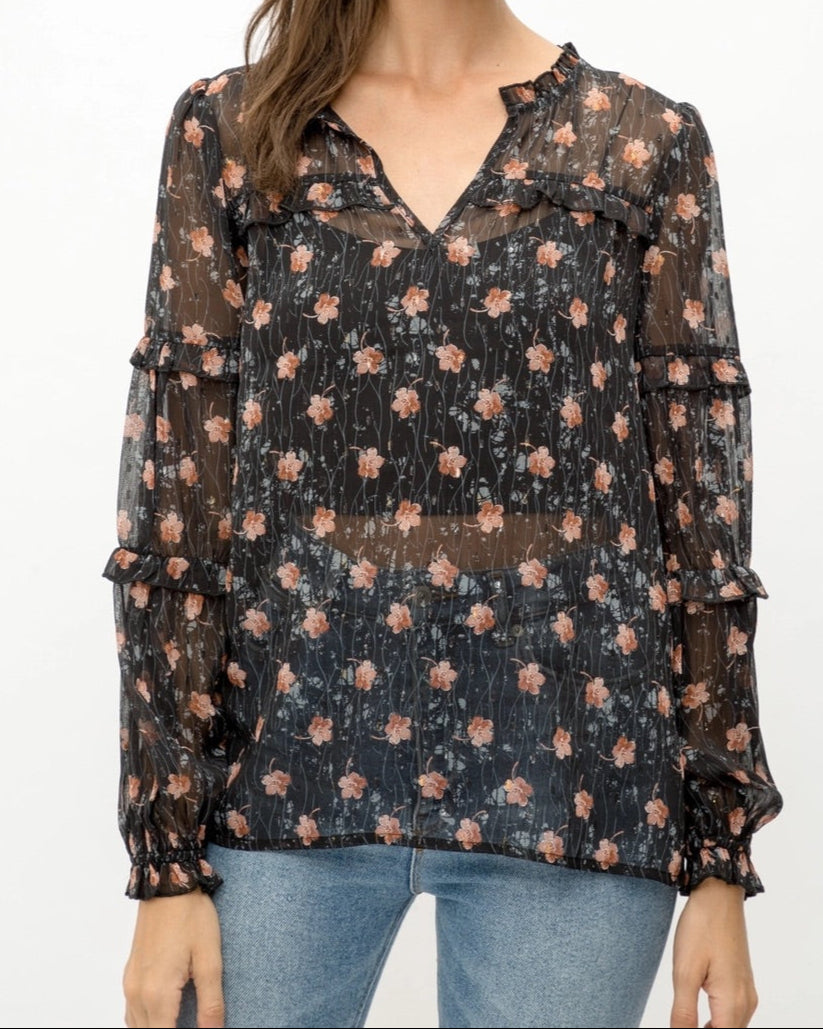 Woman wearing a black semi-sheer floral blouse with a white background.