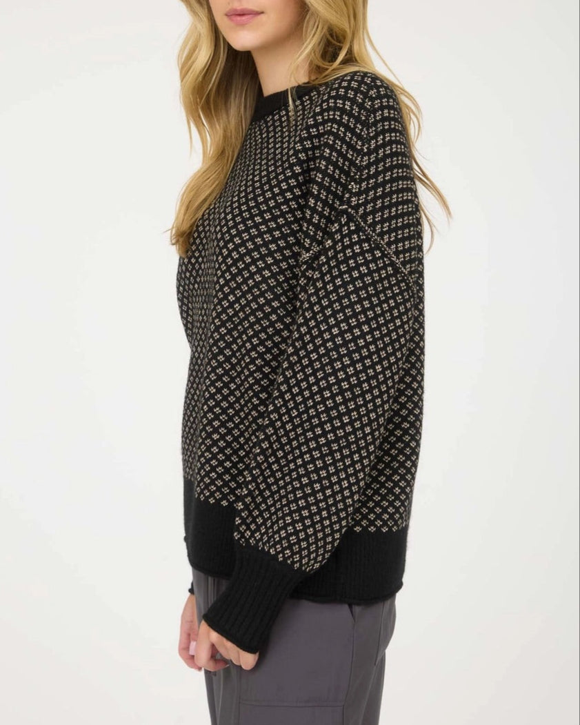Woman wearing a black patterned sweater on a white background.
