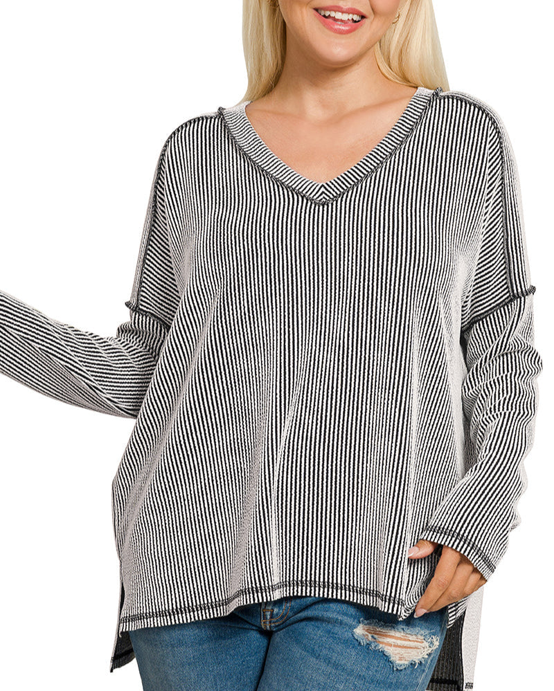 Woman wearing Plus size black and white raised rib V-neck long sleeve top with hi-low raw hem and exposed seams.