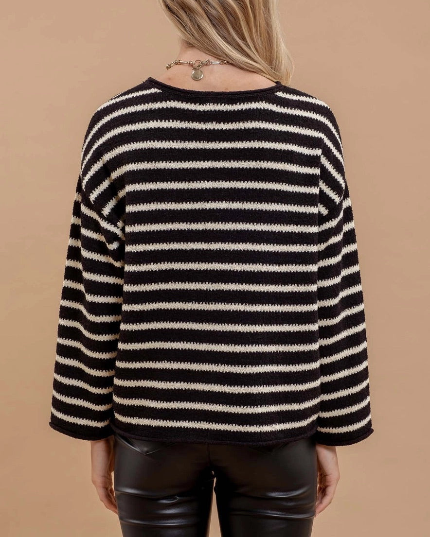 Person wearing a black and white striped sweater against a brown background.