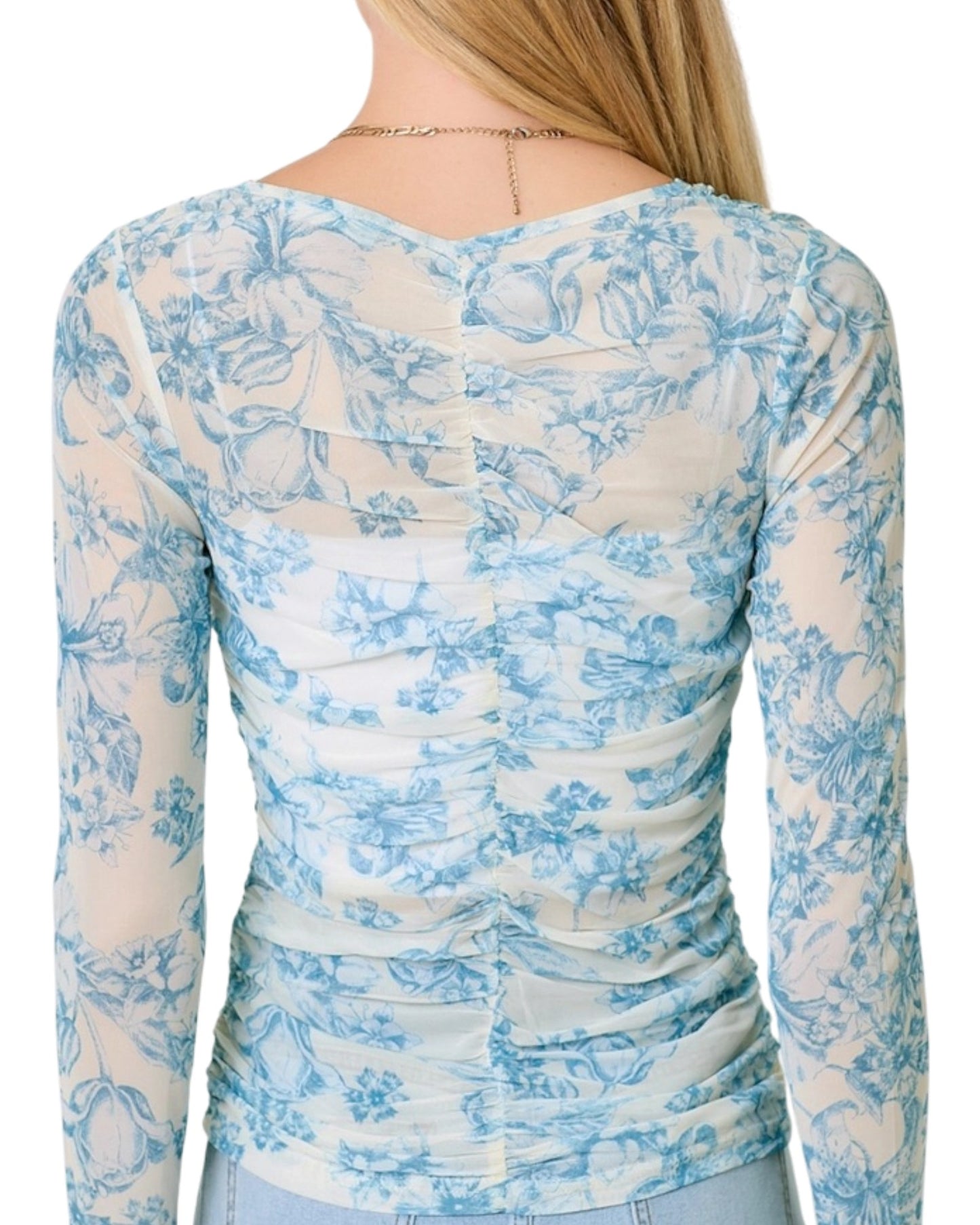 Woman wearing a white and blue floral long-sleeve top on a white background.