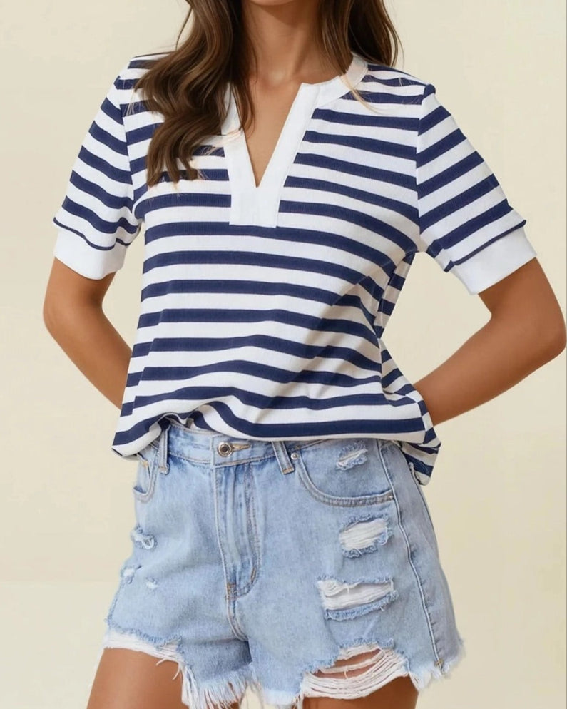 Woman wearing a striped shirt and denim shorts against a beige background.