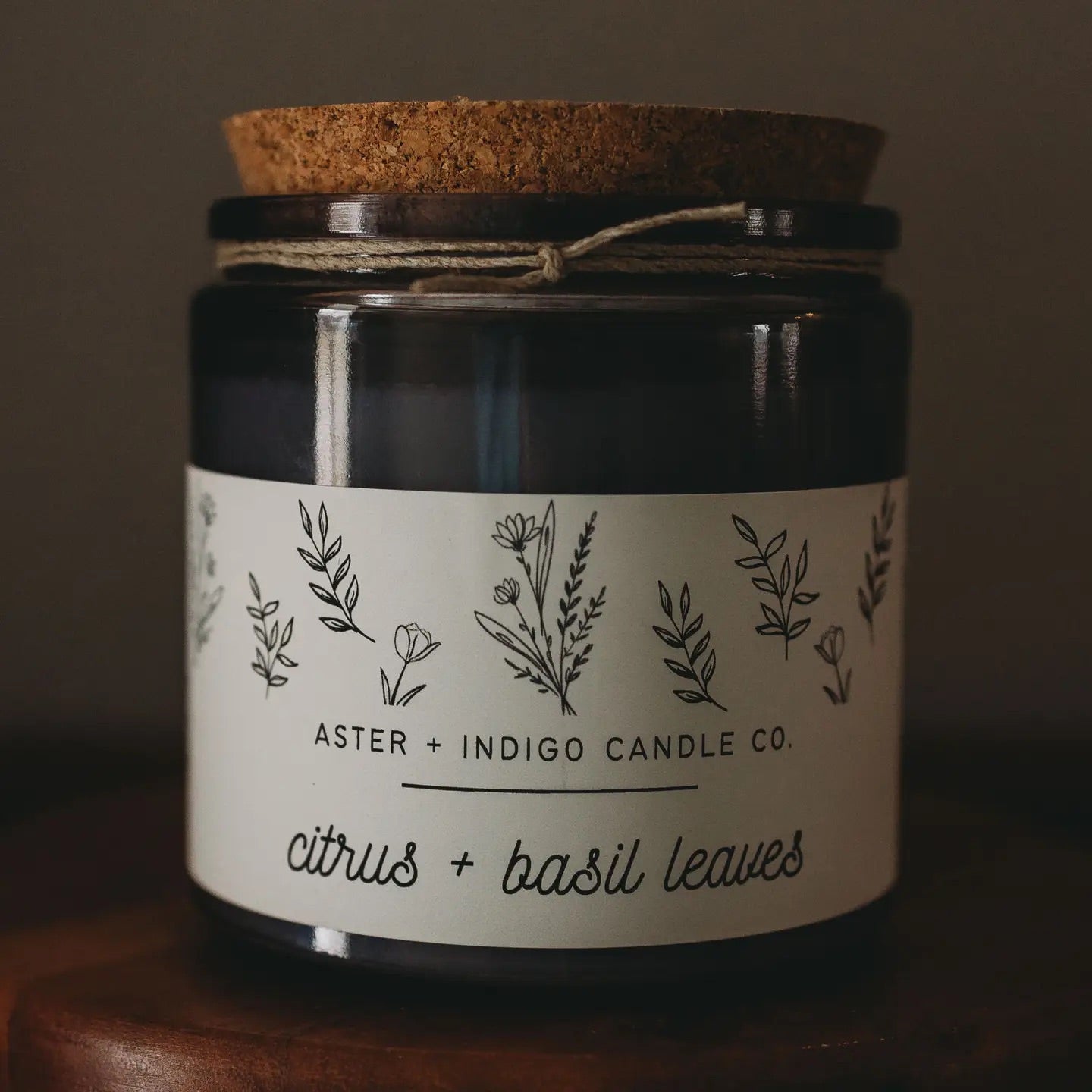 Aster + Indigo 12oz soy candle in a glass jar with cork lid, hand-poured and eco-friendly, available in various scents.