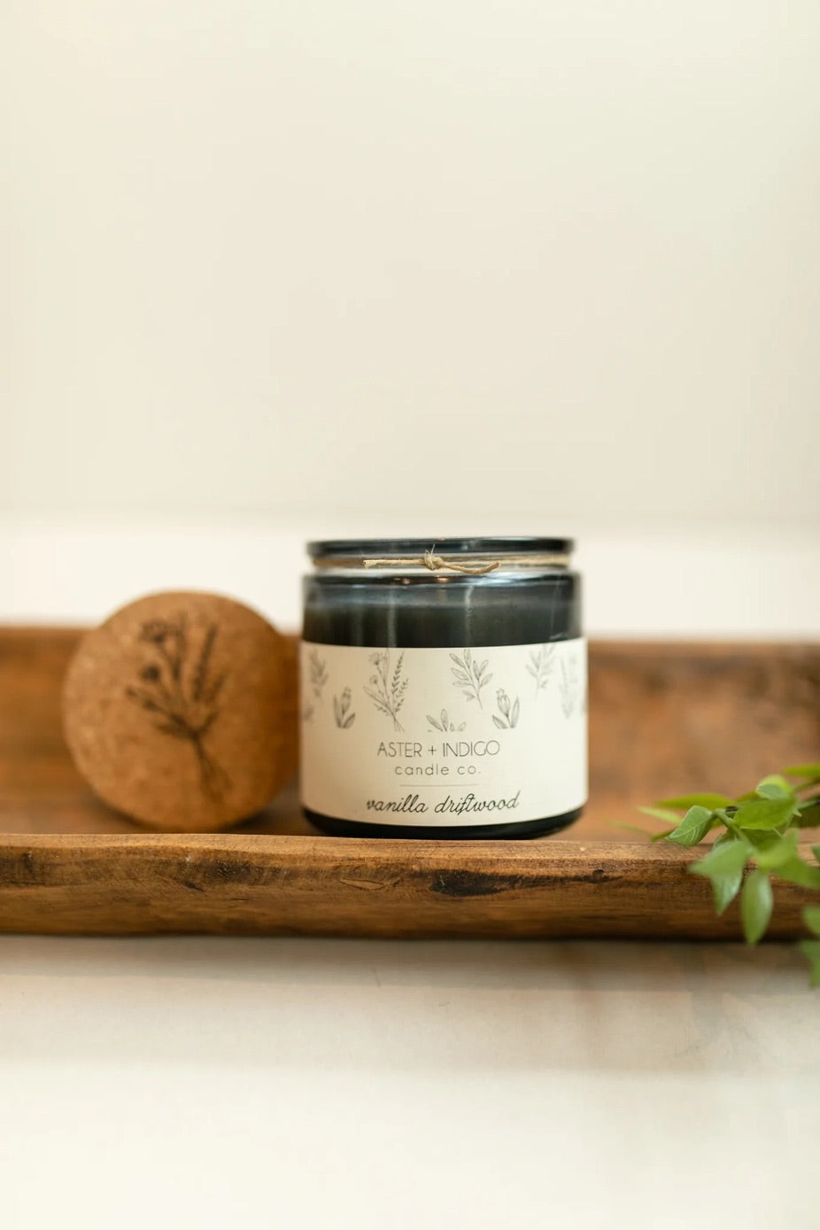 Aster + Indigo 12oz soy candle in a glass jar with cork lid, hand-poured and eco-friendly, available in various scents.