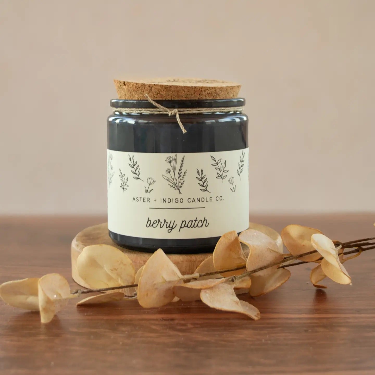Aster + Indigo 12oz soy candle in a glass jar with cork lid, hand-poured and eco-friendly, available in various scents.
