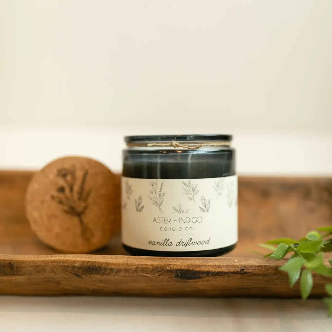 Aster + Indigo 12oz soy candle in a glass jar with cork lid, hand-poured and eco-friendly, available in various scents.