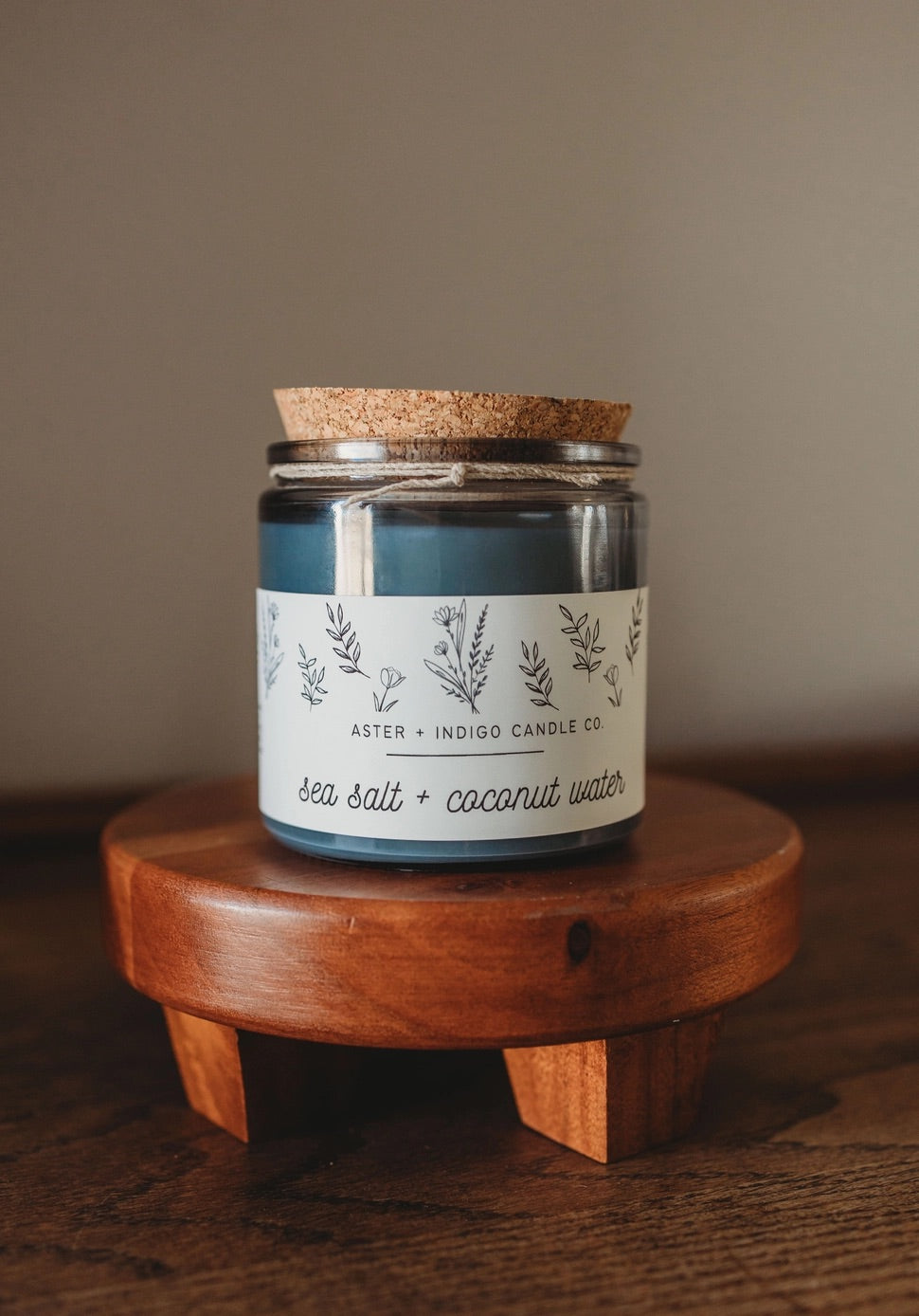 Aster + Indigo 12oz soy candle in a glass jar with cork lid, hand-poured and eco-friendly, available in various scents.
