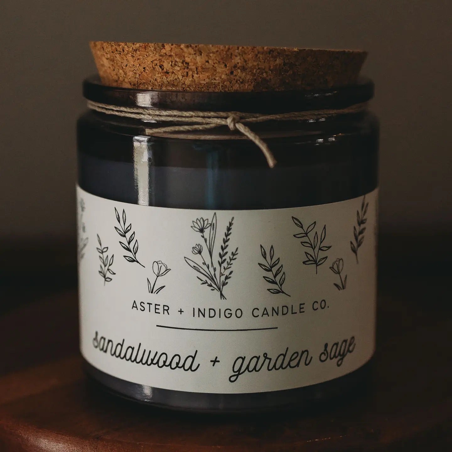 Aster + Indigo 12oz soy candle in a glass jar with cork lid, hand-poured and eco-friendly, available in various scents.