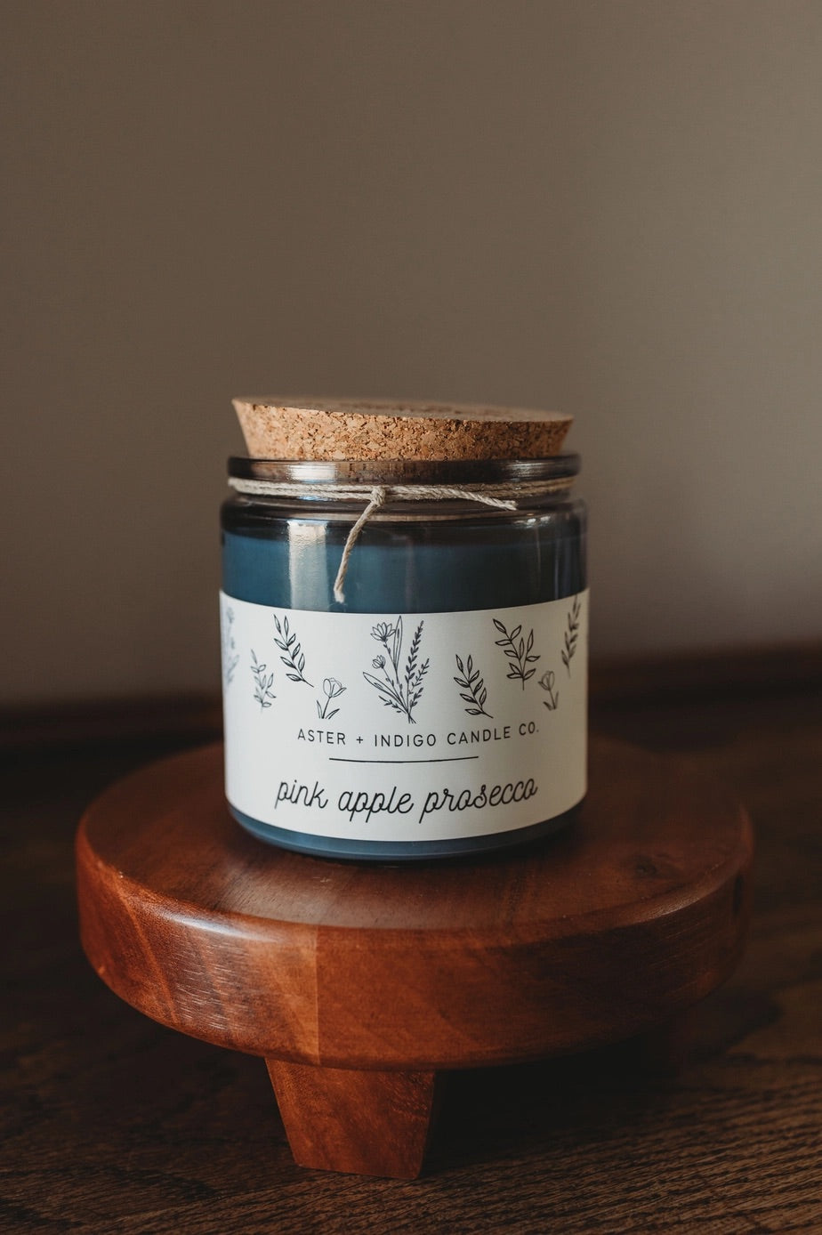 Aster + Indigo 12oz soy candle in a glass jar with cork lid, hand-poured and eco-friendly, available in various scents.