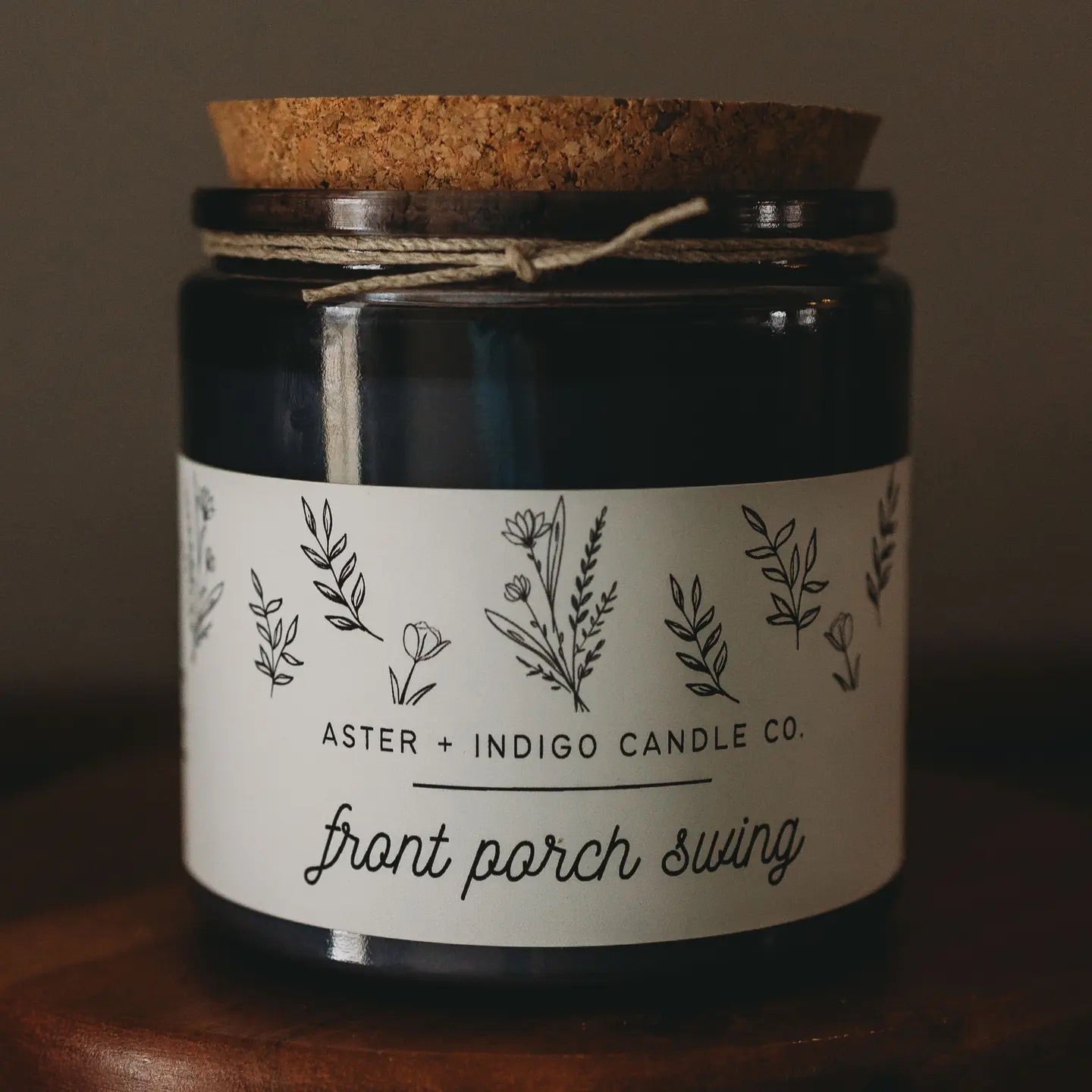 Aster + Indigo 12oz soy candle in a glass jar with cork lid, hand-poured and eco-friendly, available in various scents.