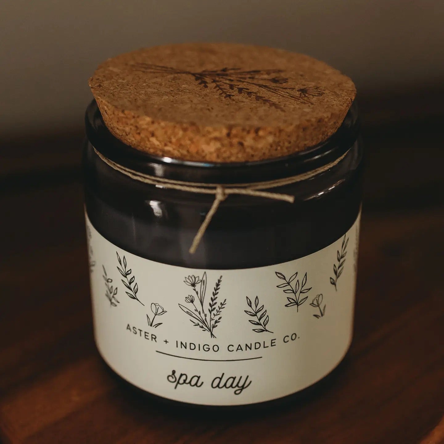 Aster + Indigo 12oz soy candle in a glass jar with cork lid, hand-poured and eco-friendly, available in various scents.