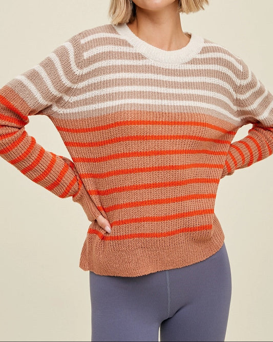 Woman wearing a striped sweater with coral and beige colors on a beige background.