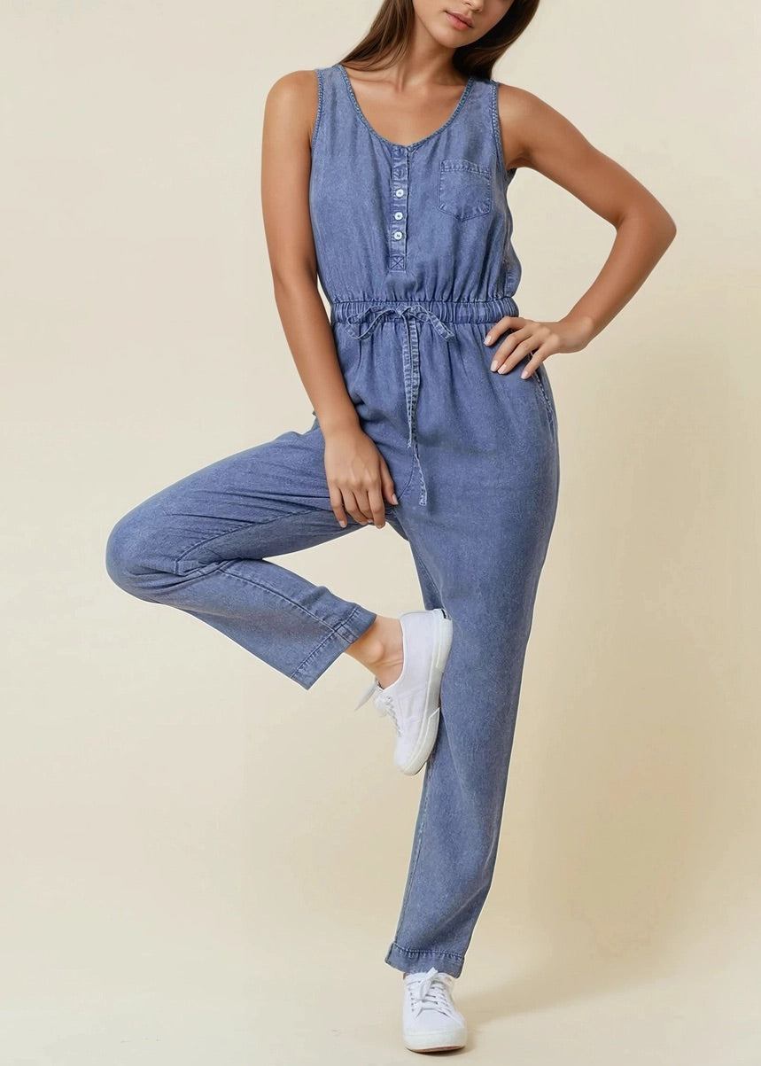 Sleeveless medium wash denim jumpsuit with scoop neck and drawstring waist.