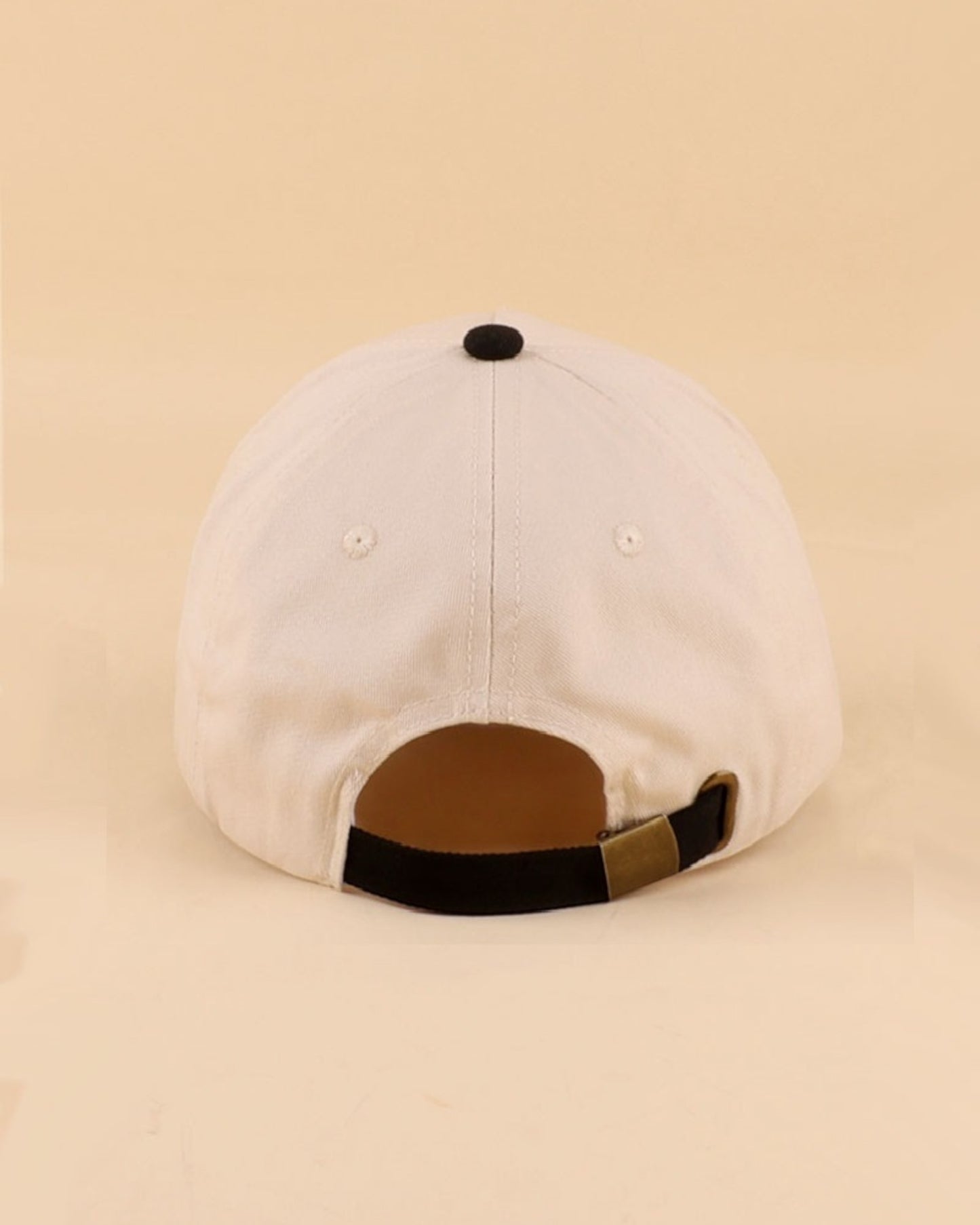 Cream and black baseball cap on a beige background.