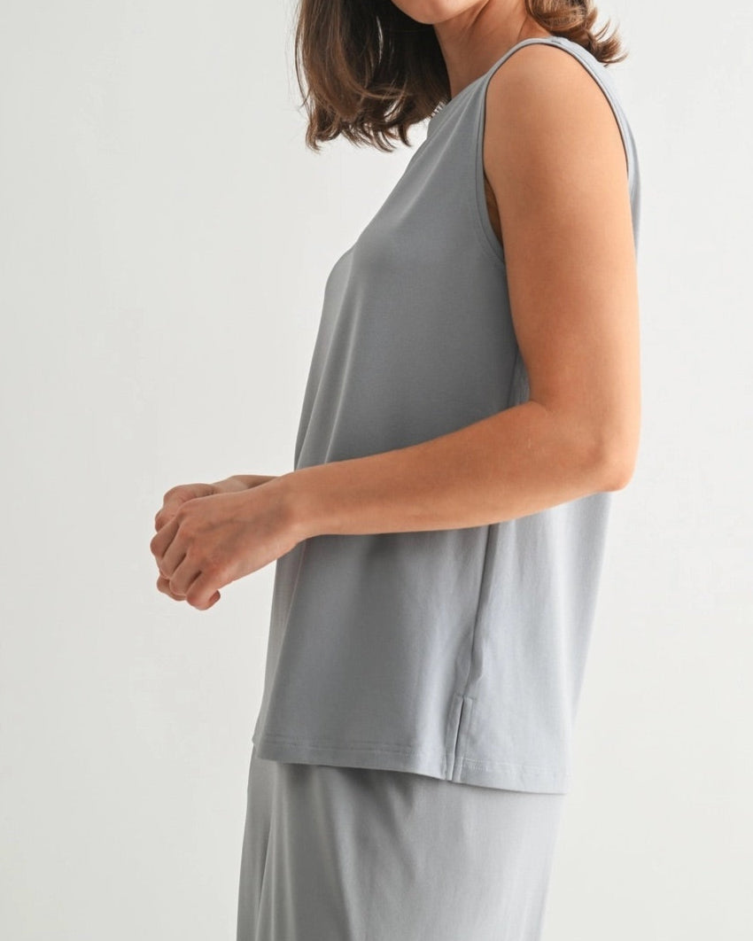 Woman wearing a dusty blue sleeveless lounge tank with relaxed drape and soft stretch.