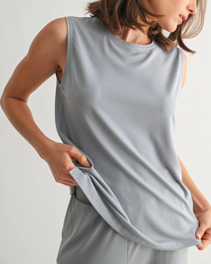 Woman wearing a dusty blue sleeveless lounge tank with relaxed drape and soft stretch.