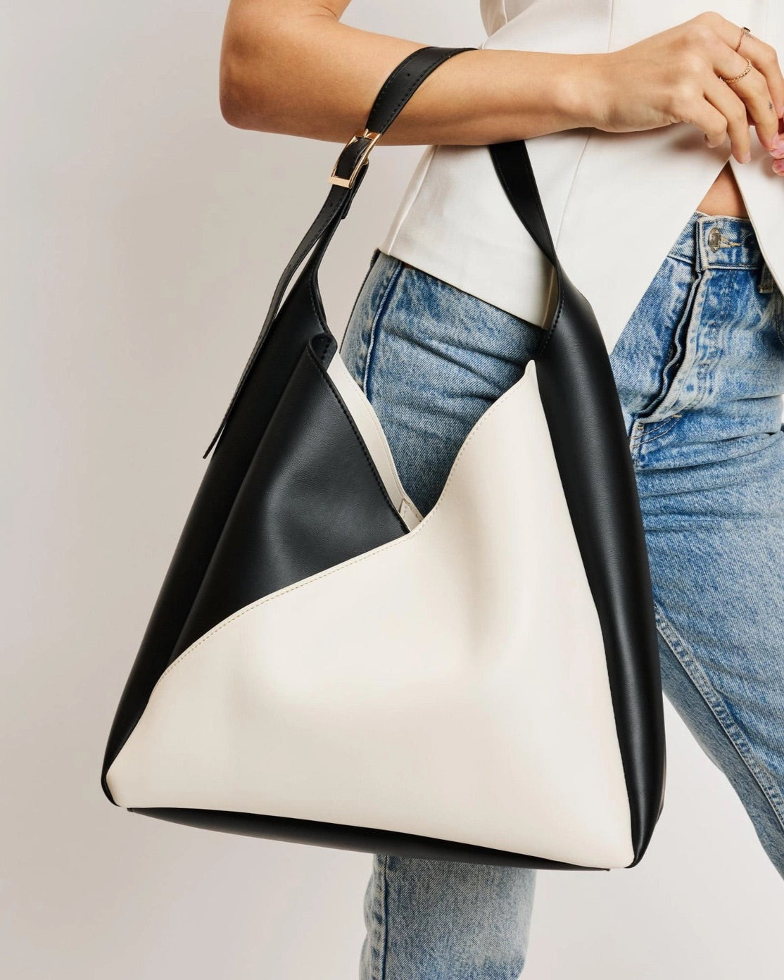 Black and white handbag held by a person wearing jeans and a white top.