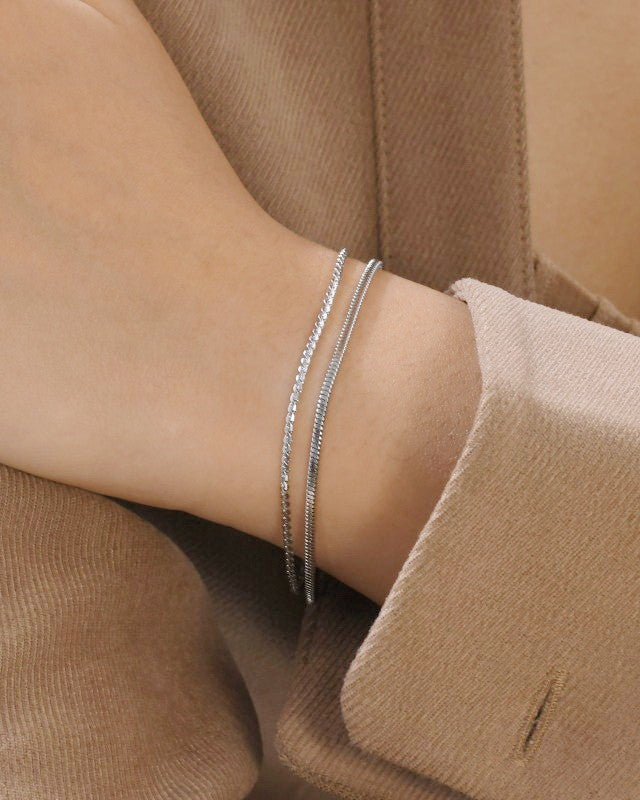 Silver bracelet on a wrist with a neutral background