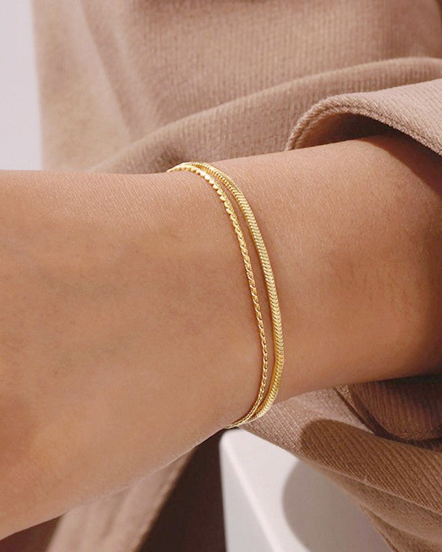 Gold bracelet on a person's wrist with a neutral background