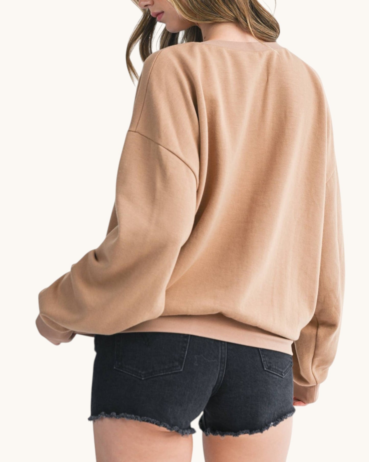 Back view of a woman wearing a brown sweatshirt and black denim shorts.