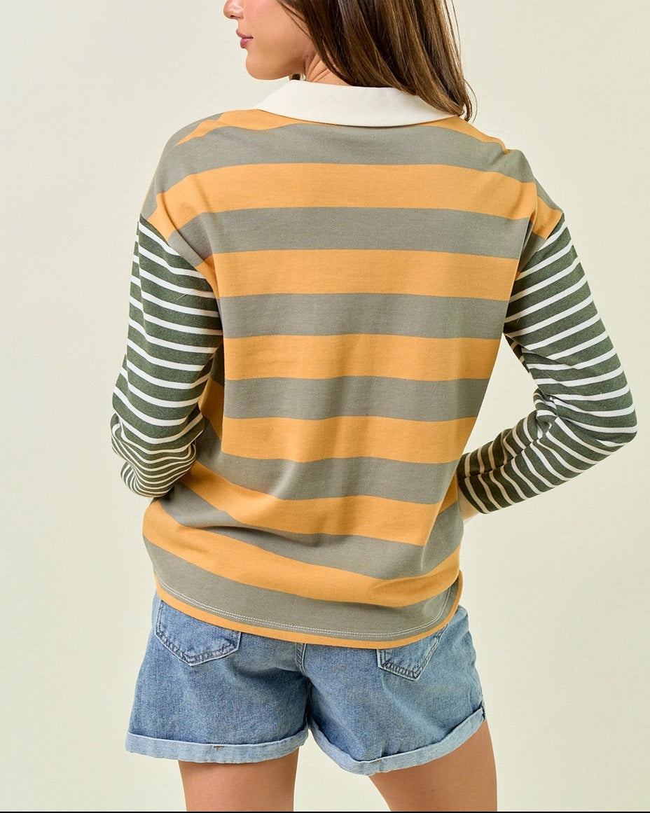 Woman wearing a muted green and mustard yellow striped rugby style shirt.