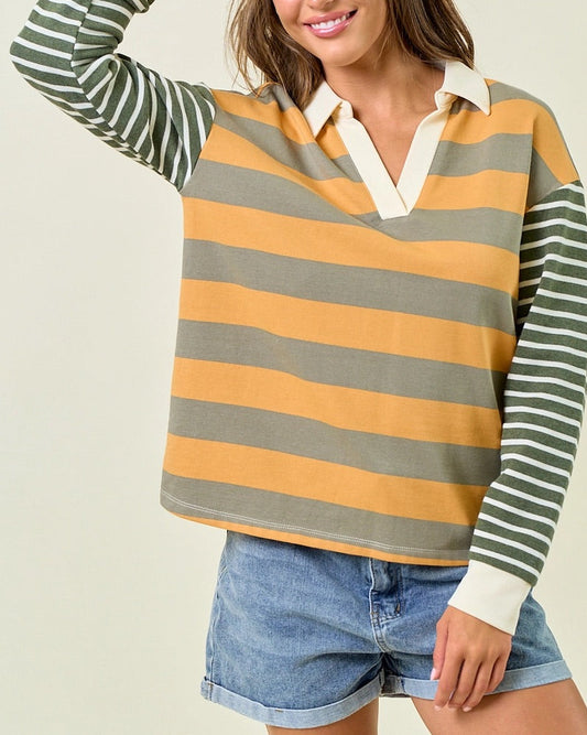 Woman wearing a muted green and mustard yellow striped rugby style shirt.