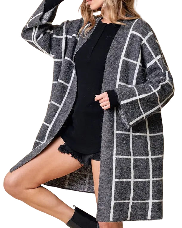Woman wearing a gray and white checkered/grid open cardigan.