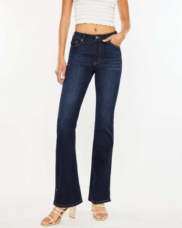 Woman wearing Kan Can Dark Wash High Rise Bootcut Jeans with side slit detail.