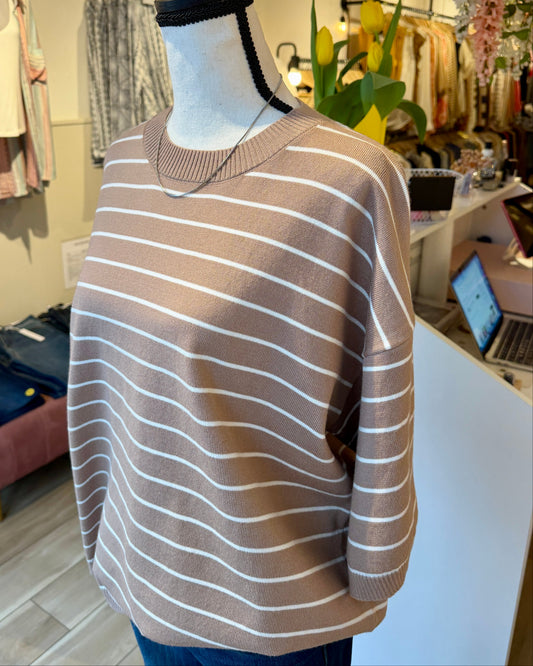 Mannequin wearing a taupe and white striped sweater in a store setting.
