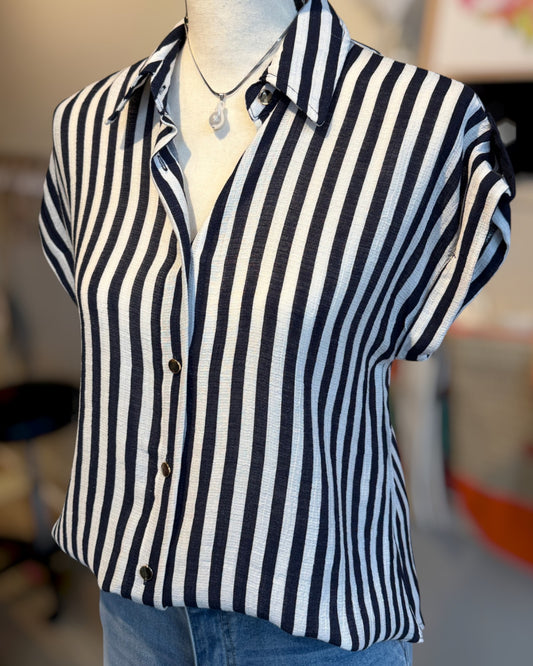 Mannequin wearing a Navy and white striped shirt with a blurred background.