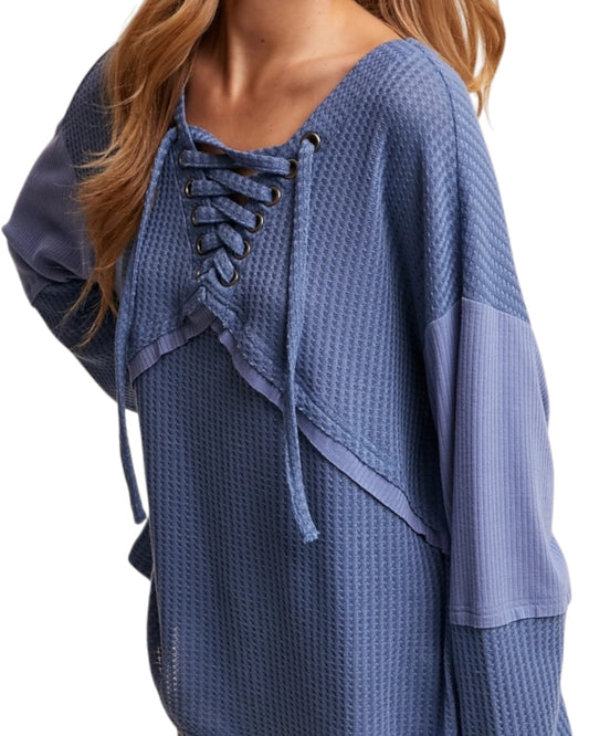 Blue textured top with lace-up front on a white background.
