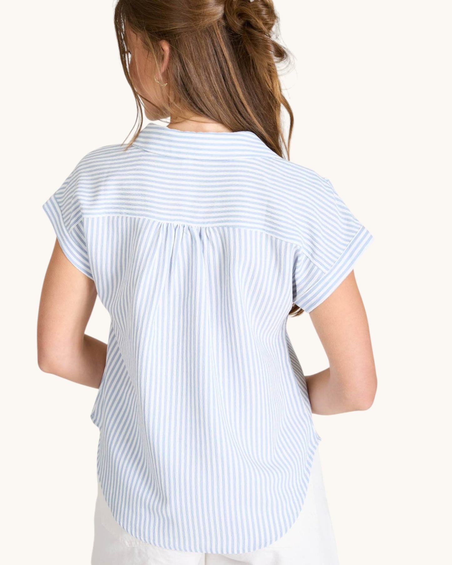 Woman wearing a light blue and white striped shirt on a white background.