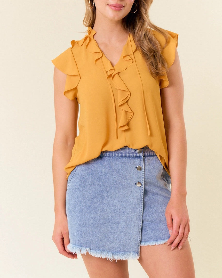 This image features a charming marigold yellow ruffle tie front tank top, paired stylishly with a blue denim skirt. The tank top is designed with delicate ruffle detailing along the neckline and sleeves, adding a feminine touch to its chic and casual look.