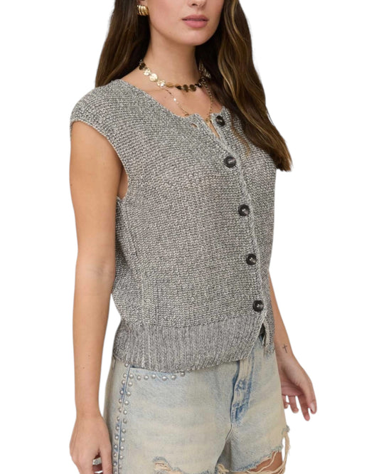 Woman wearing a gray knitted vest with black buttons on a white background.