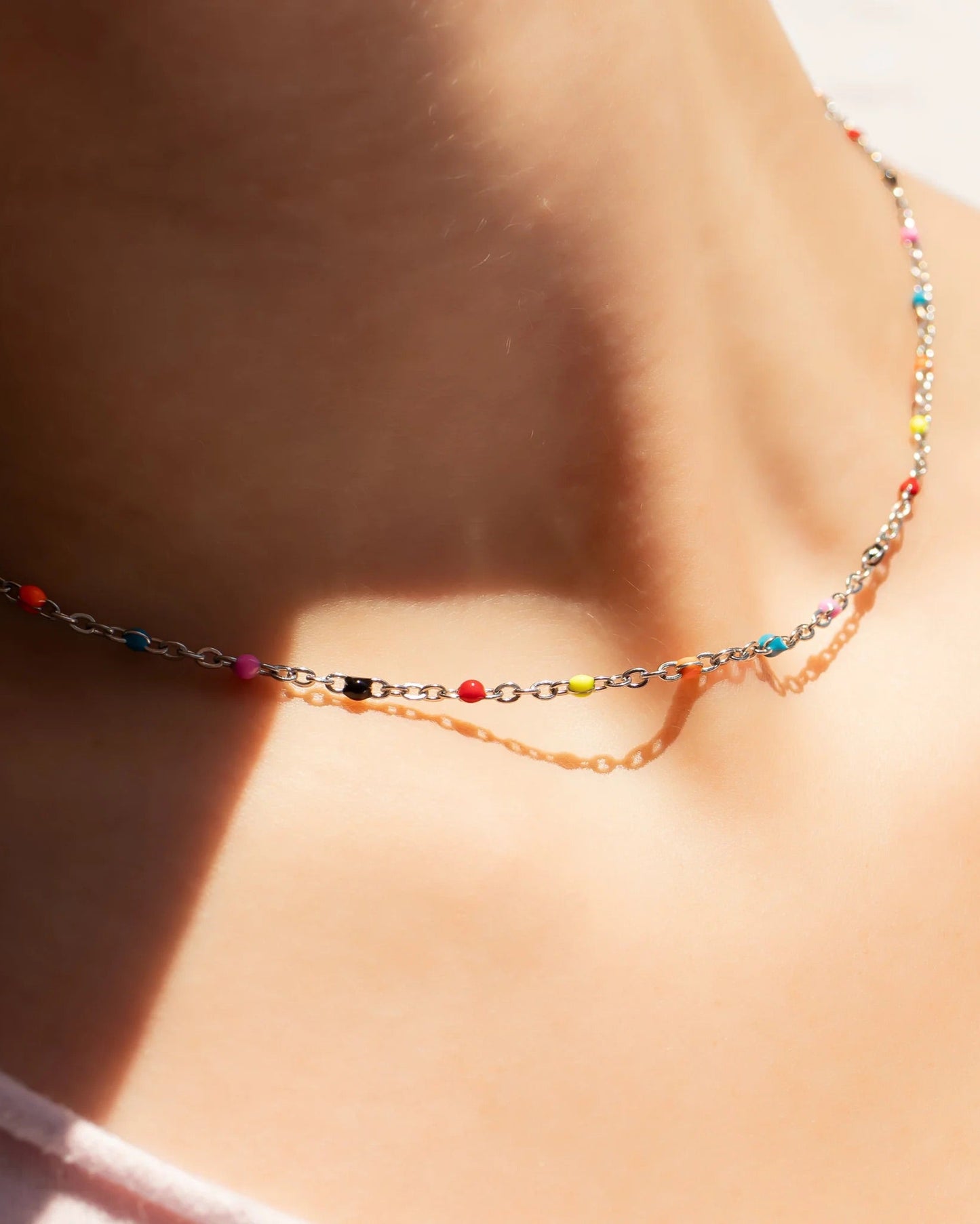 Silver necklace with colorful beads worn by a person.