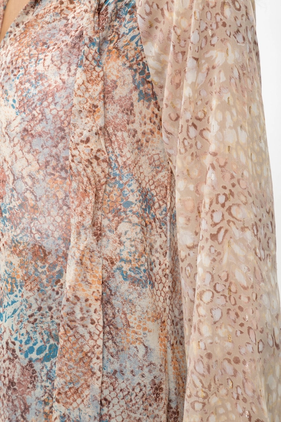 Close-up of animal print patterned fabric with earthy tones on a plain background.