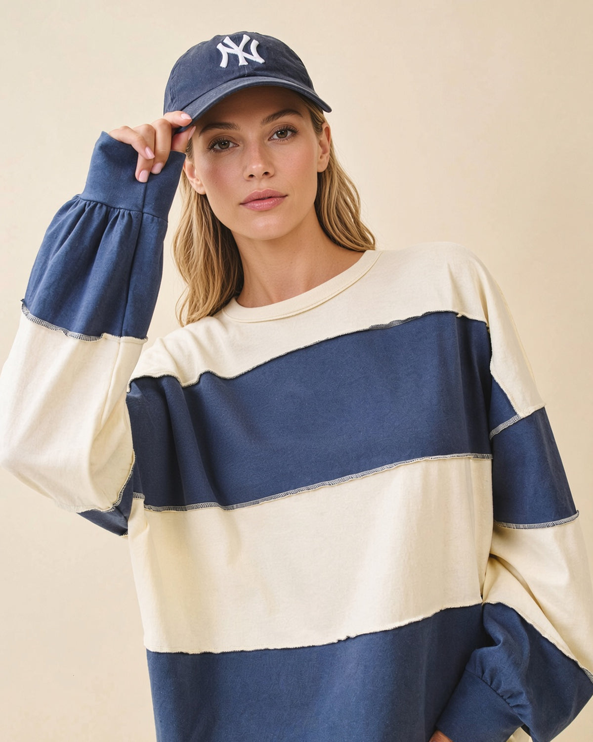 Model wearing an oversized navy and butter color block pullover with exposed seams and long sleeves.