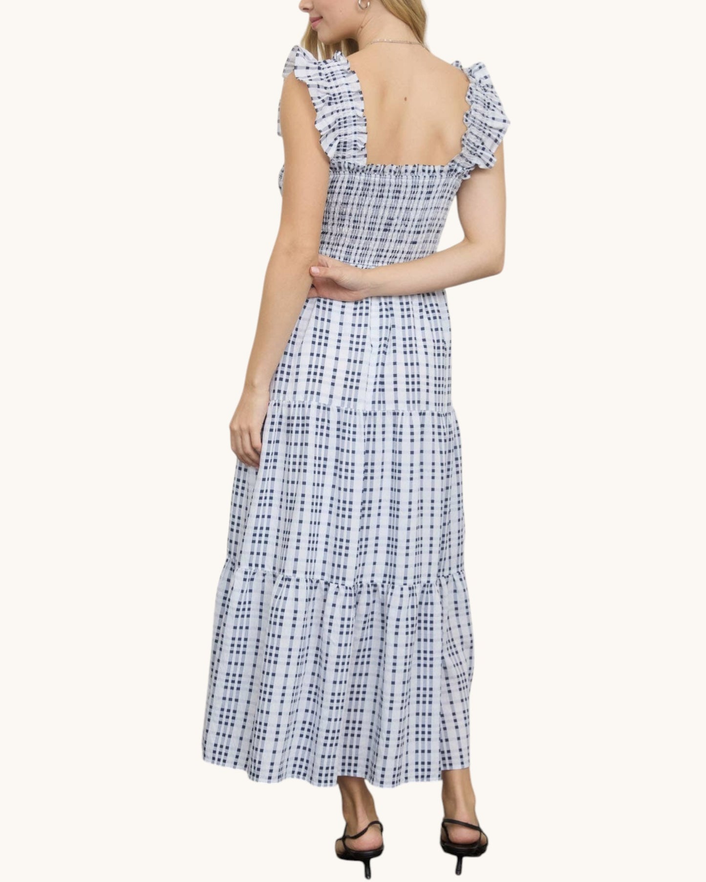Woman wearing a blue and white checkered dress on a white background.