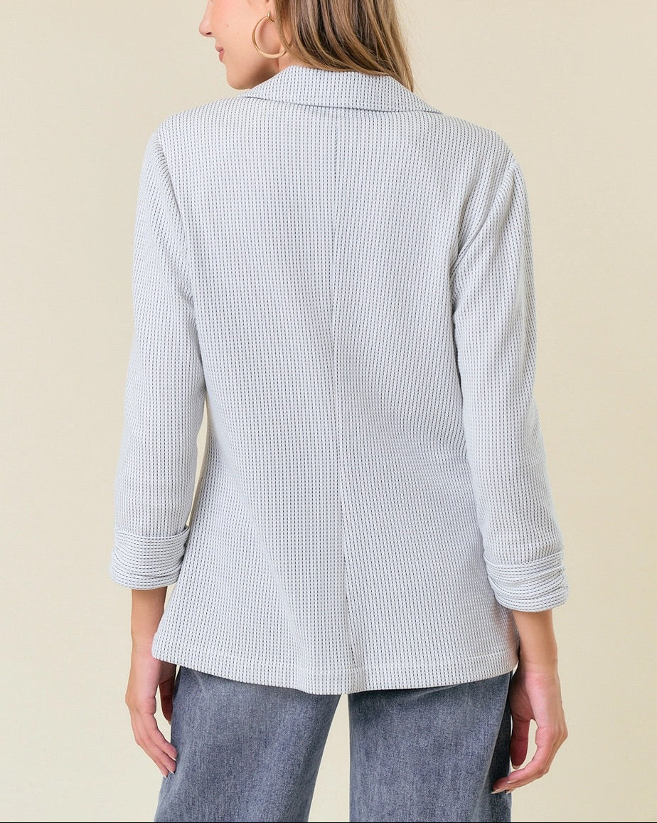 Off-white ribbed knit blazer with shirred sleeves and single-button closure.