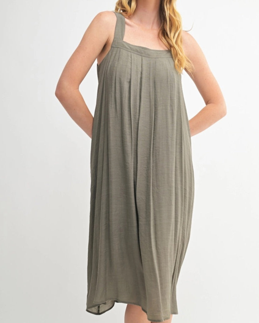 Woman wearing an Olive Green square neck midi dress with wide straps and pleats.