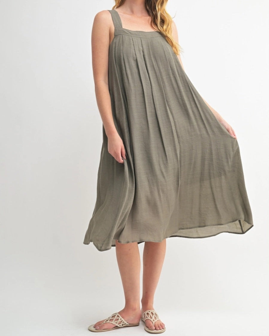 Woman wearing an Olive Green square neck midi dress with wide straps and pleats.