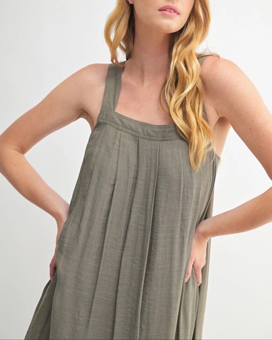 Woman wearing an Olive Green square neck midi dress with wide straps and pleats.