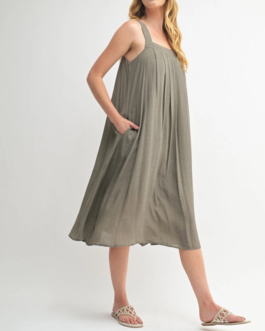 Woman wearing an Olive Green square neck midi dress with wide straps and pleats.