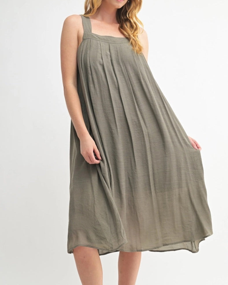 Woman wearing an Olive Green square neck midi dress with wide straps and pleats.